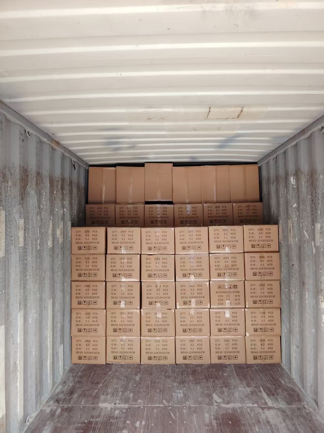 Interior view down the length of a container showing cartons stacked toward the doors