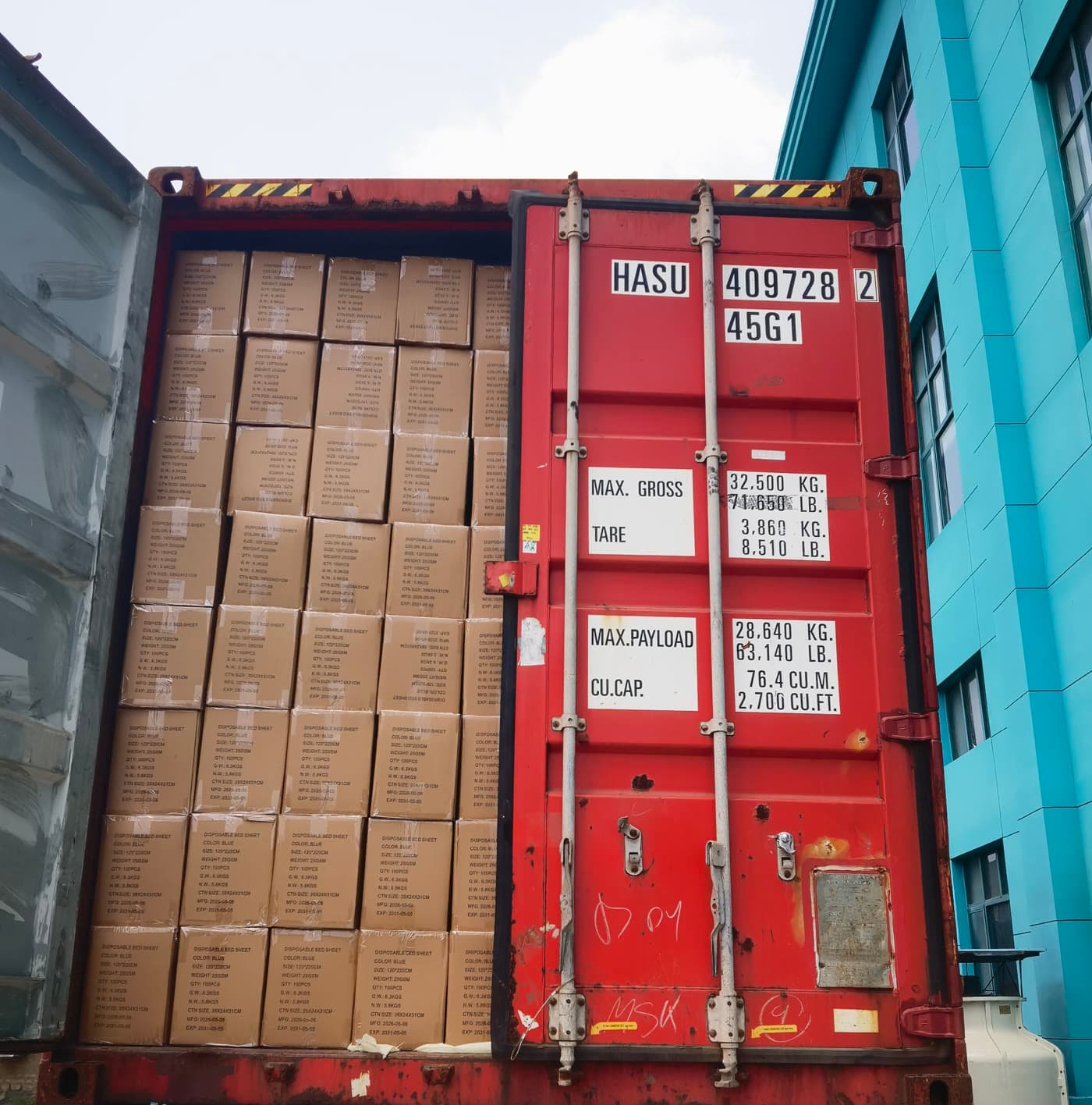 A red container packed with cartons of medical supplies behind a half-closed door