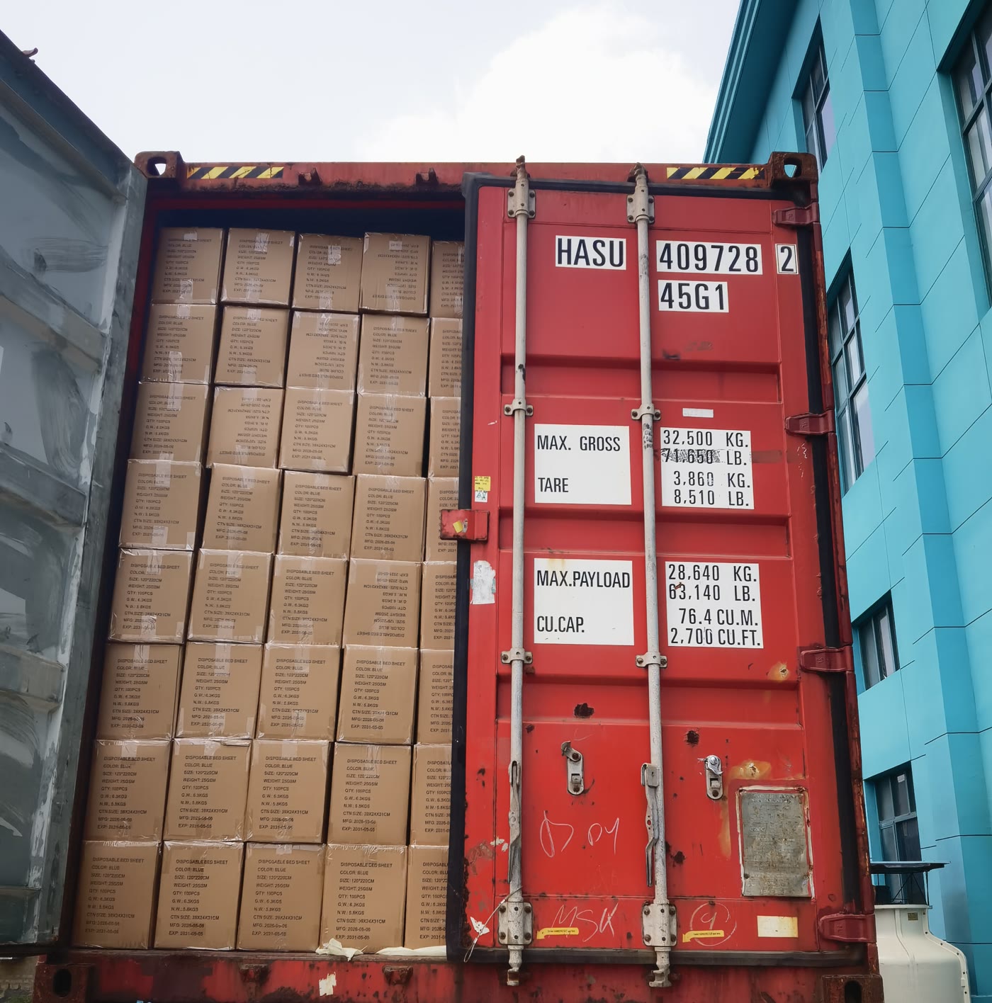 A red container packed with cartons of medical supplies behind a half-closed door