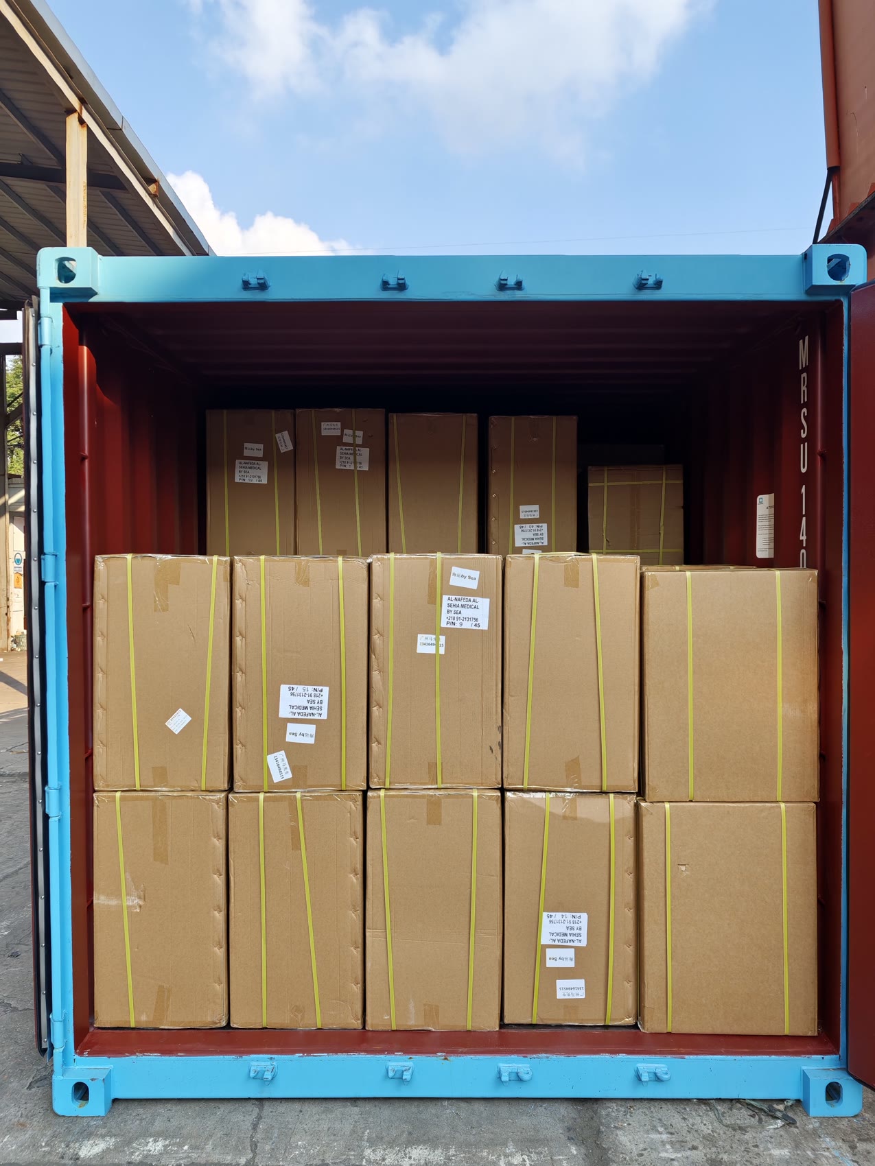 Container three in daylight: large cartons stacked from the floor to near the roof